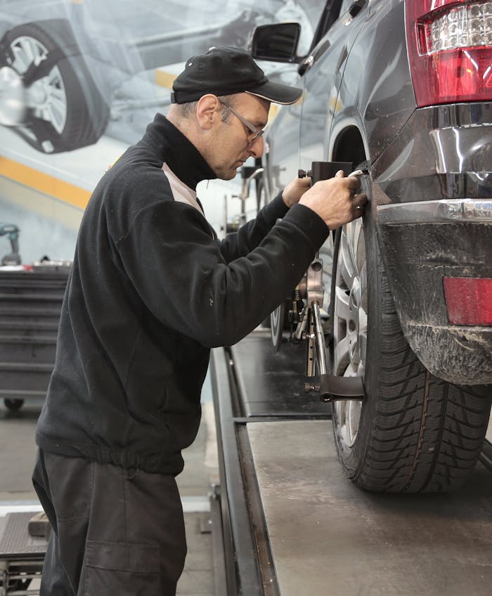 Side view of a mechanic aligning a car tire in a professional auto workshop.